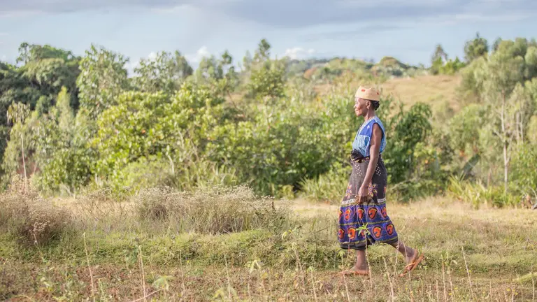 Woman walking through a field wearing traditional dress.