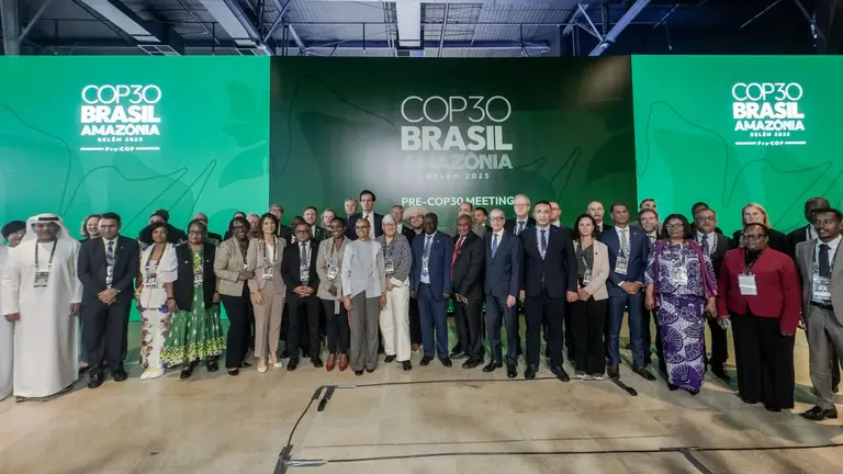 Large group of people posing for a photo in front of a big sign that reads 'COP30 Brazil Amazonia'.
