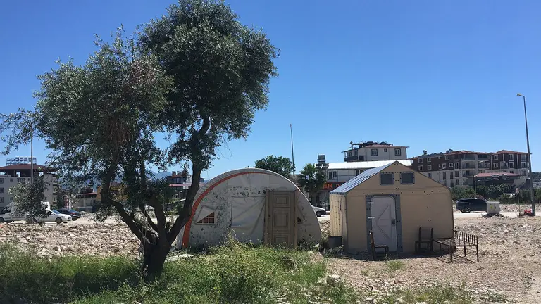 Two tent-like buildings are constructed on stony ground. 