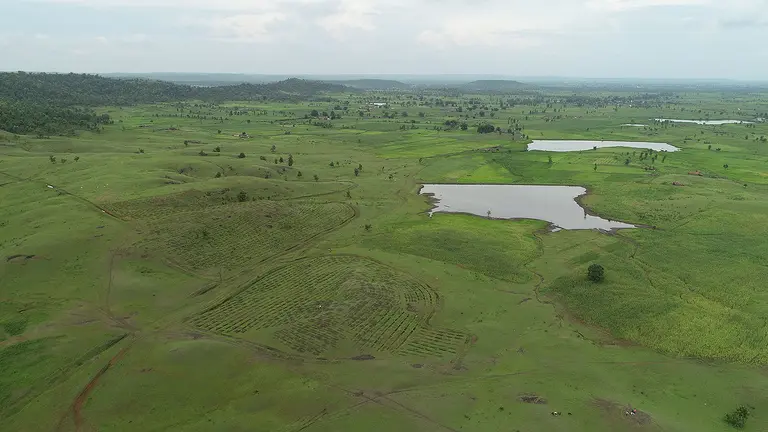 An aerial view of extended fields on which there are two small pools of water.