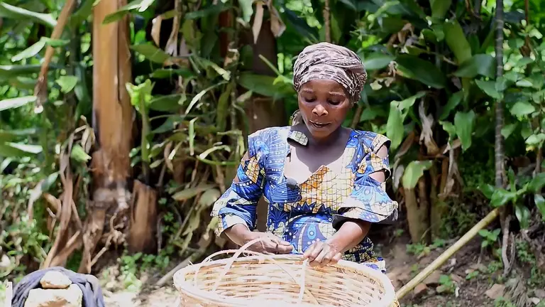 A woman weaves a basket by hand.