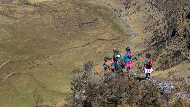 An aerial photo of a group of people in the distance, standing on hillside outcrop and overlooking a valley.