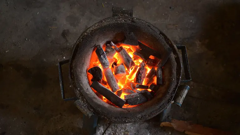 A close-up of charcoal burning in a cooking pot.