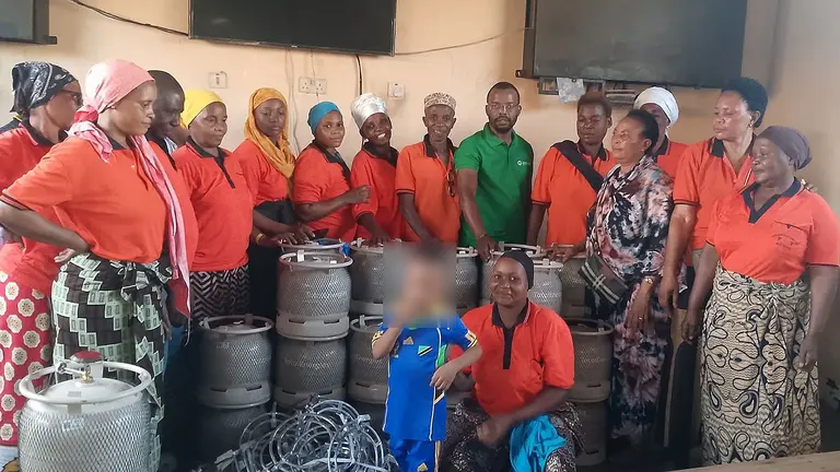 A group of women are pictured smiling along with some gas cylinders for cooking.