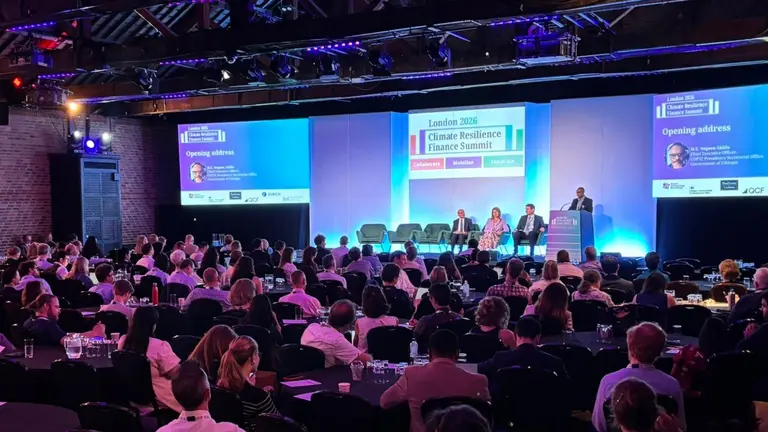 Panel discussion during the opening plenary of the London Climate Resilience Finance Summit 2026. Four speakers are standing on stage while the audience watches. A big screen is projecting the summit logo on the background.