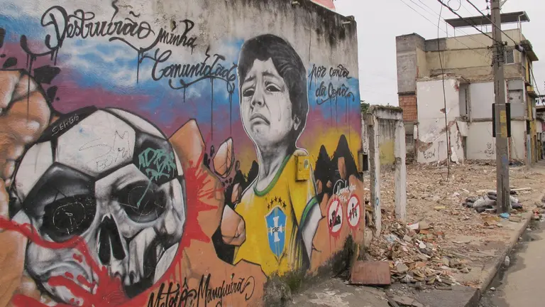 Image of grafitti of child crying on a building in Favela Metro-Mangueira. The buildings next to it are torn down.