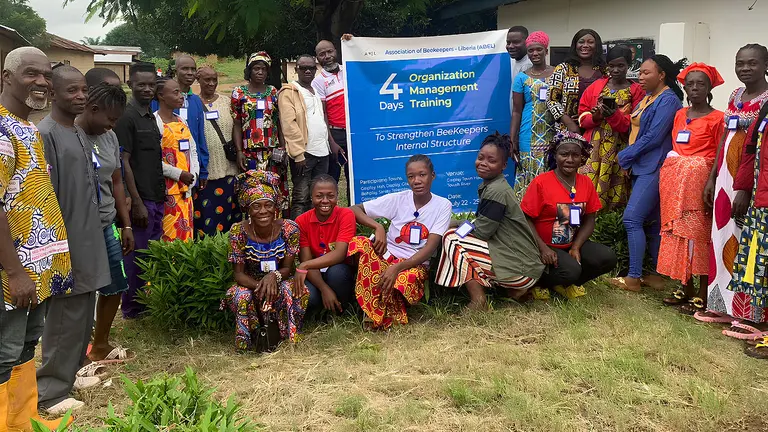 Men and women pose alongside a banner for the Twah River Beekeepers Association.
