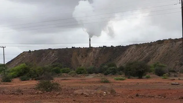 A chimney stack in the distance pours out smoke.