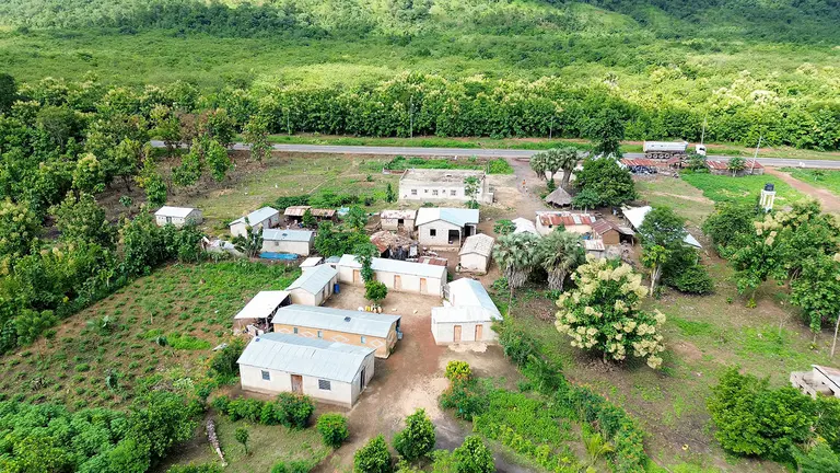 An overhead view of a series of white houses and the surrounding fields with crops.