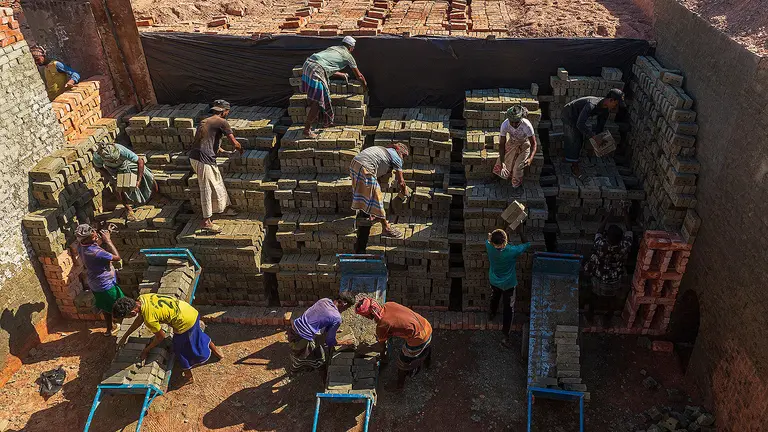 Workers toil to line up thousands of bricks under a hot sun.