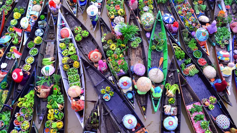 An aerial view of an array of colours displayed by traders as they sell food and their wares from boats. 