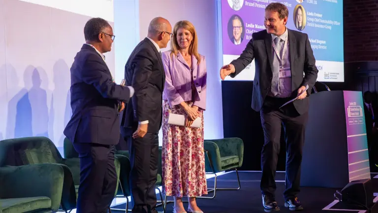 Panel members dressed in smart attire shacking hands.
