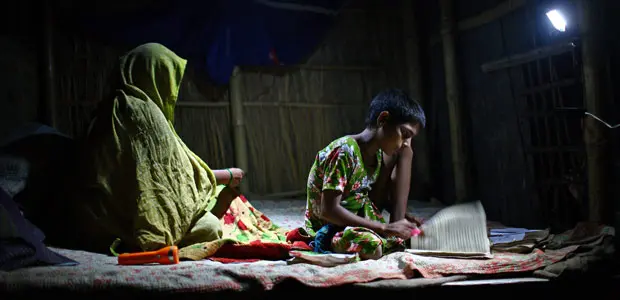 A girl studies under the light of a rechargeable solar lamp