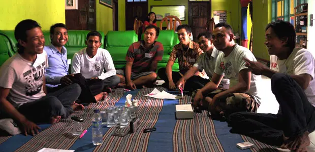 Men from Blitar, a city in East Java, Indonesia, sit in a circle on mats.   