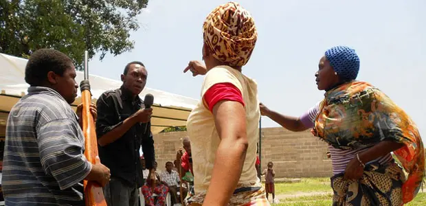 People gesture and point at a man with a microphone.