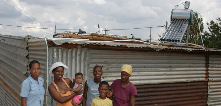 South Africa: Anna with friends and family in front of her new solar water heating system. It is often more cost-effective to provide energy services to poor communities via off-grid sources (Photo: Abri le Roux, Creative Commons via Flickr)