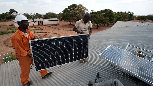 An image showing two men on the roof of a school in Zambia carrying out a macrosolar installation. Sustainable energy solutions for Least Developed Countries were discussed at the event in London (Photo: Steve Woodward)
