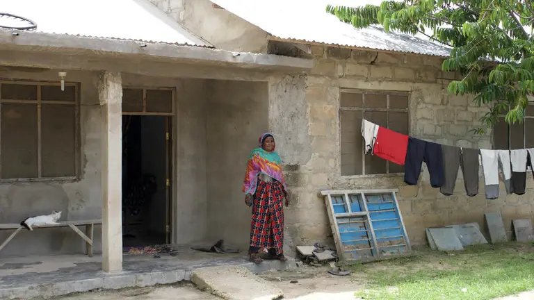 Mwanahamisi Mzalendo stands in front of her house