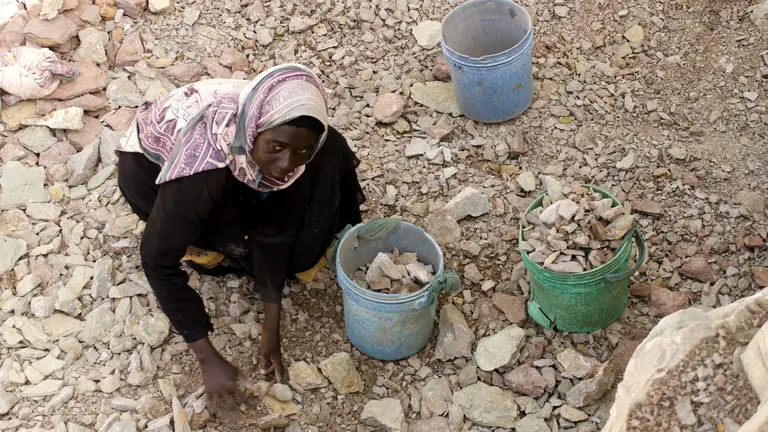 A labourer fills a bucket with limestone.