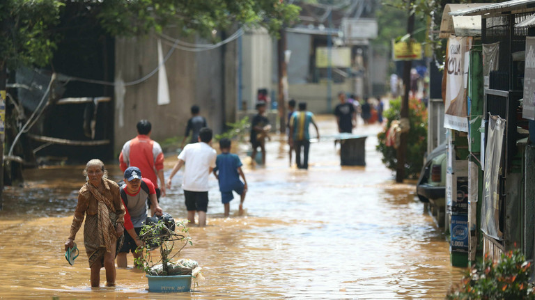 Citizens wade through a flooded road in Bandung City