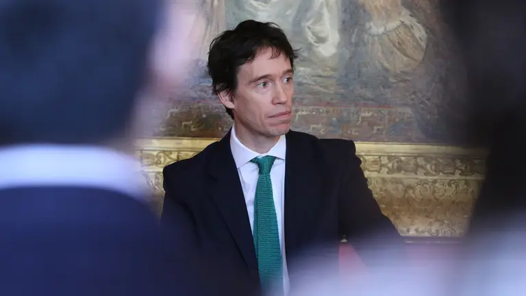 A photo of a man addressing a conference, pictured through the heads of those listening