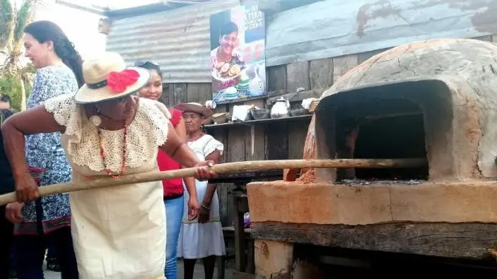 A women puts food into an outdoor oven