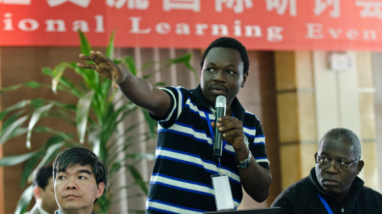 An African man makes a speech in front of a banner in Chinese