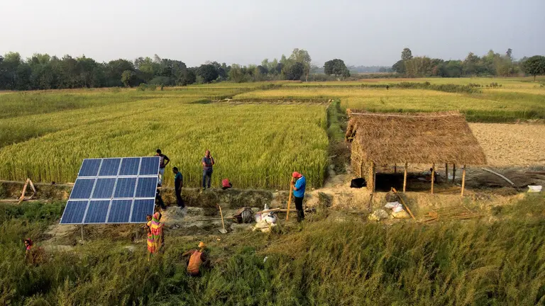 People installing solar panels in a field