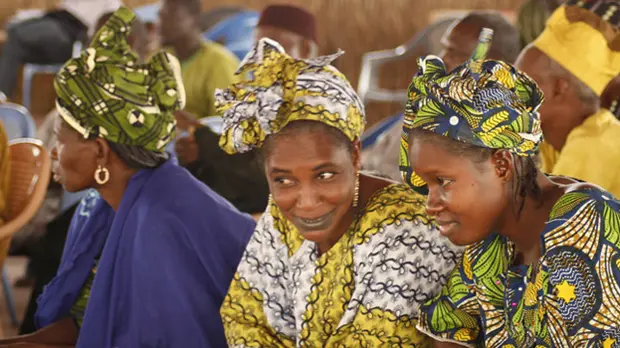 Two women talking to each other at a crowded event.