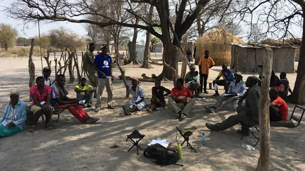 A group of men and women gathered under some trees