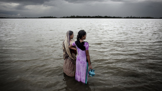 Two women look out over the rising sea water