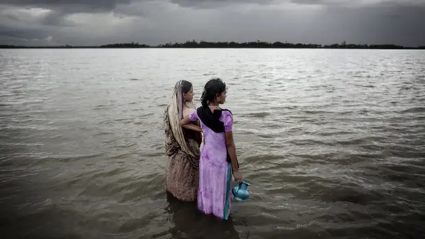 Two women look out over the rising sea water