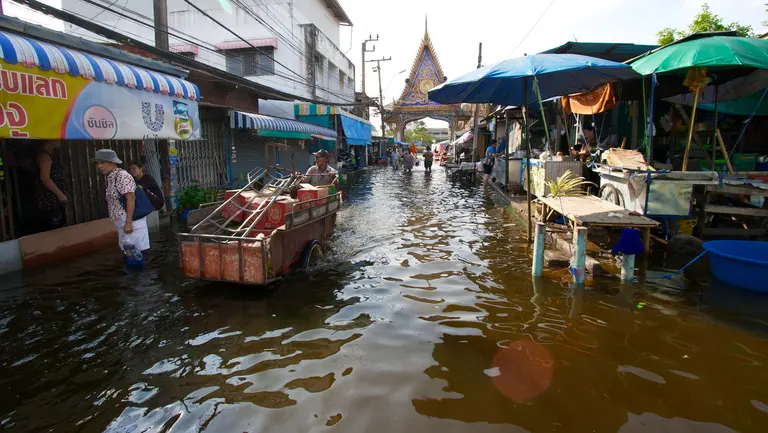 A trader wades through knee-high flooded water in a marketplace