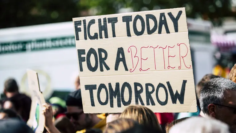 A handwritten sign is help up saying "Fight today for a better tomorrow"