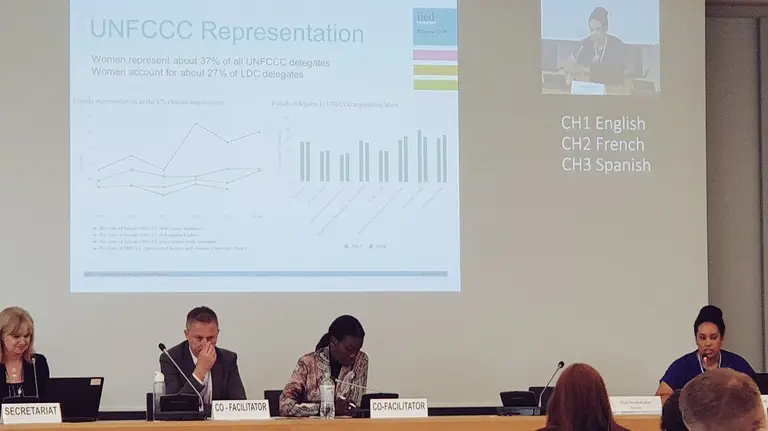Seated panellists give a presentation in front of a giant screen