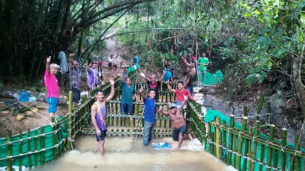 Men posing for a photo while constructing a weir with bamboo structures.