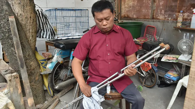 A seated man cleaning a crutch.