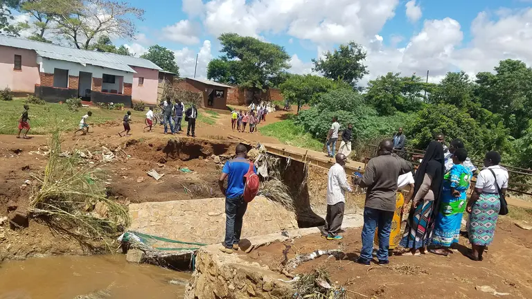 A group of people looking at a damaged bridge.