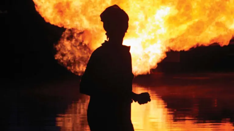 Woman silhouetted in front of gas flare