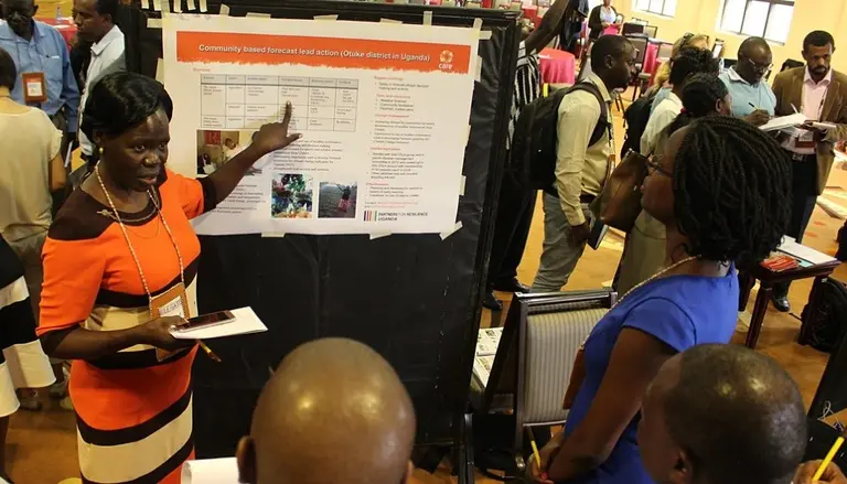 Woman in workshop points at a poster. Audience looks at her.