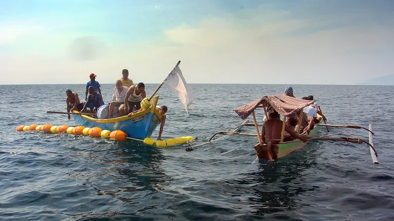 Two small boats full of fishers on the water.