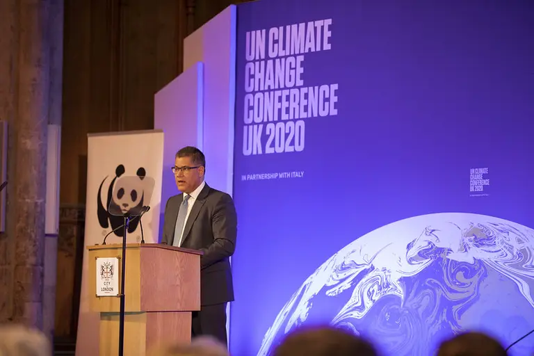Man speaking in front of a wall that reads "UN Climate Change Conference UK 2020"