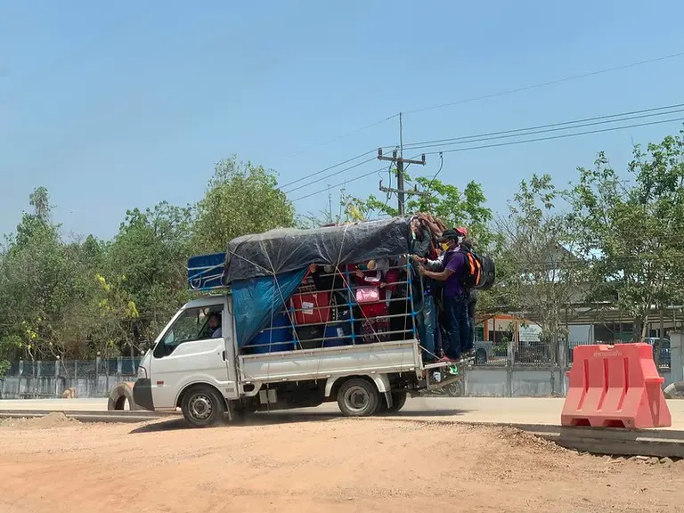 Pick-up van packed with people and suitcases.