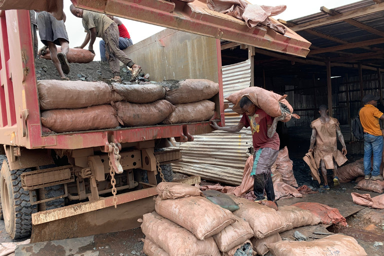 Men load a truck with heavy bags