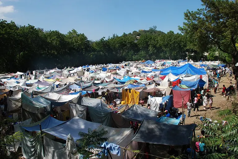 Camp site with several informal tents made of fabric and plastic.
