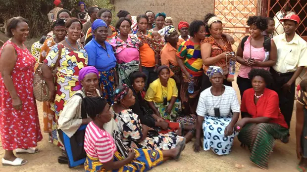 A group of women gather round the entrance to a building.