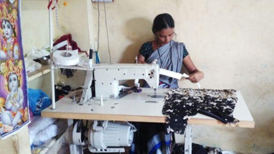 A  woman sits at a sewing machine, studying a pattern.