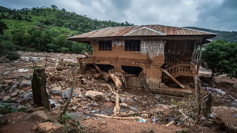 A ruined house on a hillside, surrounded by mud and rocks.