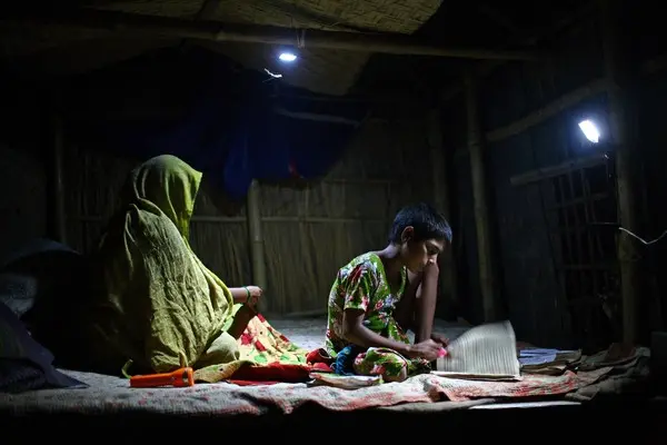 A girl studies under the light of a rechargeable solar lamp.