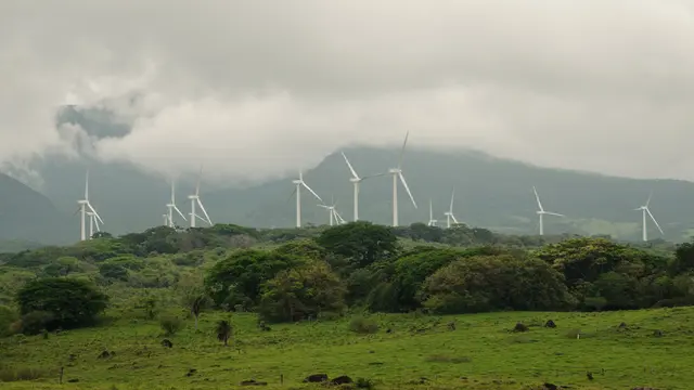 A row of wind turbines on a misty hillside.